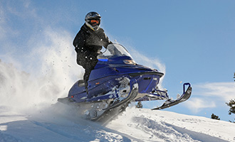 A blue snowmobile riding over the snow slopes