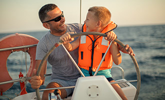 A father and on steering a boat on the ocean