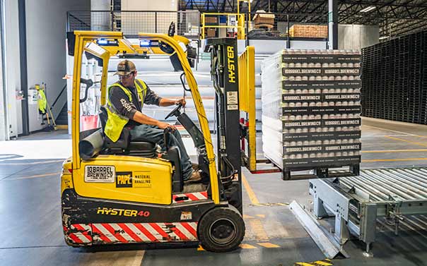 A male driving a forklift in a warehouse